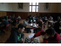 �iaci sediaci v dvojiciach pri stoloch hraj� �achov� z�pasy