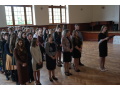 Žiaci IV.A a IV.B s triednymi profesorkami nastúpení v aule školy a žiačka IV.B počas príhovoru