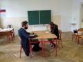 Dvaja �iaci sediaci za stolom po�as hrania rol� v �stnej �asti s��a�e