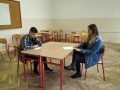 Dvaja �iaci sediaci za stolom po�as hrania rol� v �stnej �asti s��a�e